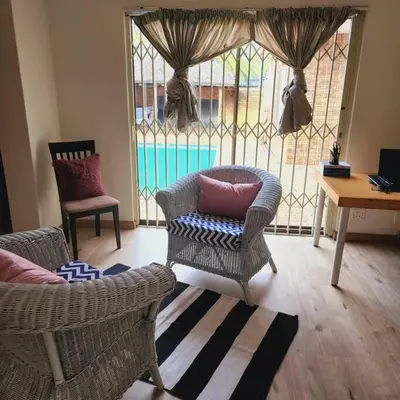 a living room with chairs and a window with a pool at Mercy's Getaway Place in Cape Town
