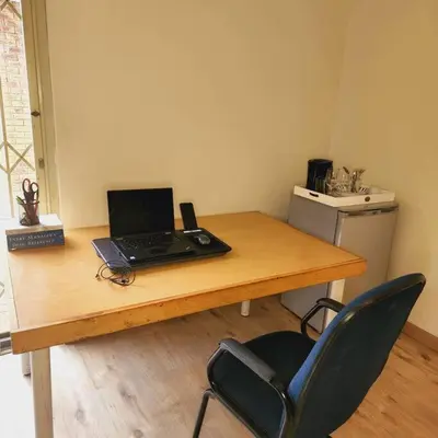 a laptop computer sitting on a wooden table with a chair at Mercy's Getaway Place in Cape Town