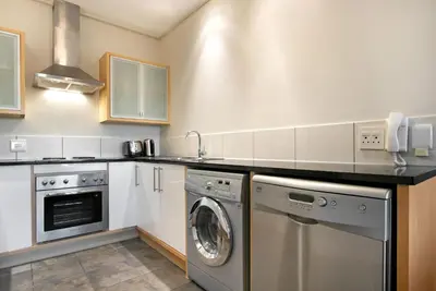 a kitchen with a washing machine and a washer at Manhattan 1003 in Cape Town