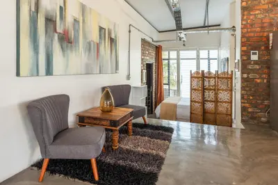 a room with two chairs and a table and a bed at Sunset-Loft in Cape Town