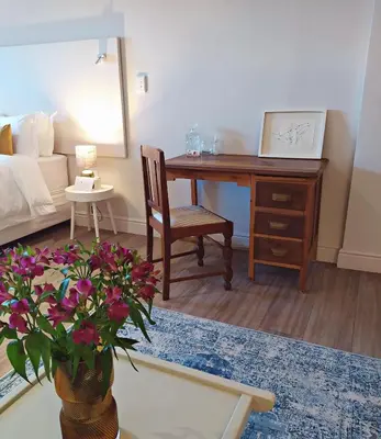 a living room with a desk and a table with flowers at Apartment at Hermanus Waterfront in Hermanus