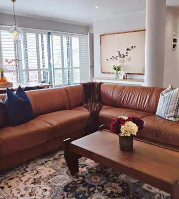 a brown leather couch in a living room with a coffee table at Apartment at Hermanus Waterfront in Hermanus