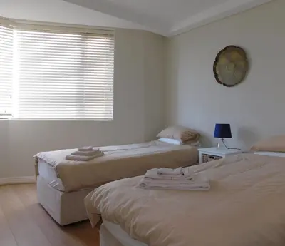 a bedroom with two beds and a window with blinds at 97 On Strand in Strand