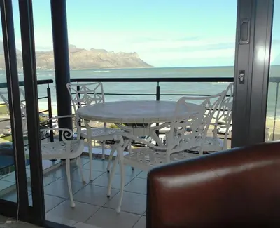a table and chairs on a balcony with a view of the ocean at 97 On Strand in Strand