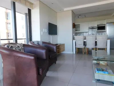 a living room with a leather couch and a kitchen at 97 On Strand in Strand