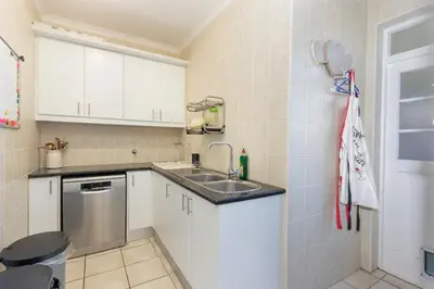 a small kitchen with white cabinets and a sink at Sunset Villa 50 in Cape Town