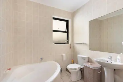 a bathroom with a tub and a toilet and a sink at Sunset Villa 50 in Cape Town