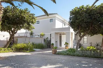 a white house with trees in front of it at Sunset Villa 50 in Cape Town