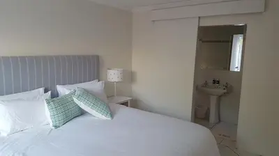 a bedroom with a white bed with pillows and a sink at Mafari Beach House in Hermanus