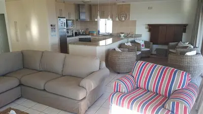 a living room with a couch and a kitchen at Mafari Beach House in Hermanus