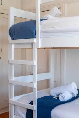 two white bunk beds with towels on them in a room at Enchanting Abode in Rosebank in Cape Town