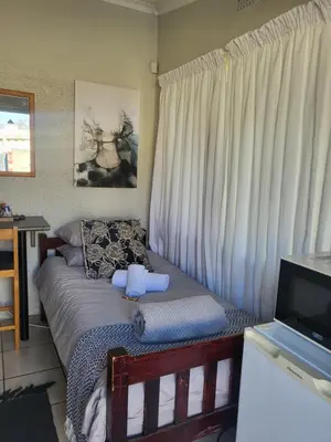 a small bedroom with a bed and a television at 9 on Oostersee in Cape Town