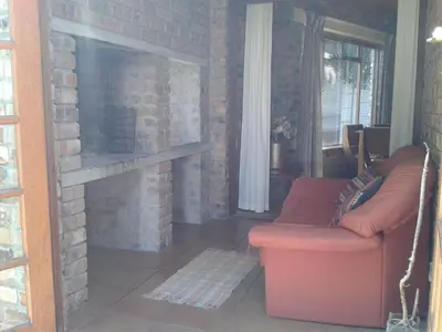 a living room with a brick fireplace and a red couch at Little Lotta Cottage in Caledon
