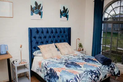 a bed with a blue headboard in a bedroom at Mooi Uitsig Lodge in Paarl