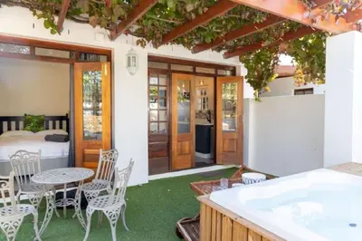a patio with a table and chairs and a bed at Mitre's Edge Orchard Suite in Klapmuts