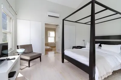 a bedroom with a black canopy bed and a chair at La Terra de Luc in Franschhoek
