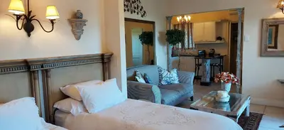 a bedroom with a bed and a living room at Roosboom Guest Apartments in Somerset West