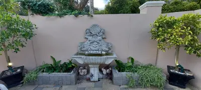 a stone fountain in front of a wall with plants at Roosboom Guest Apartments in Somerset West