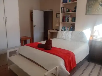 a bedroom with a bed with a red blanket at Out of Africa in Sandbaai, Hermanus in Hermanus