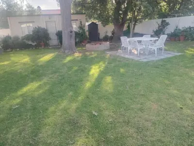 a table and chairs in a yard with a tree at Out of Africa in Sandbaai, Hermanus in Hermanus