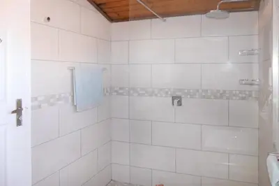 a bathroom with a shower with white tiles at Shalom Self Catering in Kleinmond