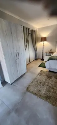 a bedroom with white cabinets and a bed and a rug at Audrey's Self-Catering Accommodation in Cape Town