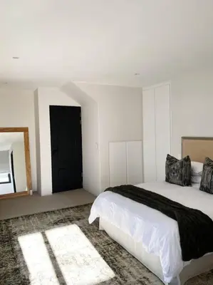 a white bedroom with a bed and a mirror at Stellenbosch - Winelands Living Solar in Stellenbosch