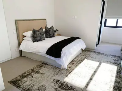 a bedroom with a bed with black and white pillows at Stellenbosch - Winelands Living Solar in Stellenbosch