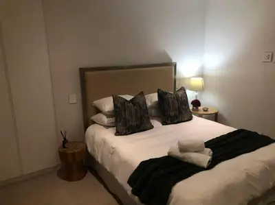 a bedroom with a large bed with black and white pillows at Stellenbosch - Winelands Living Solar in Stellenbosch