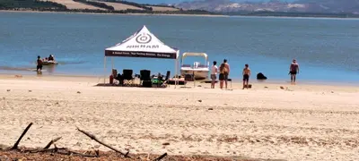 a tent on a beach with people in the water at The 10th Hole - Golf Estate in Villiersdorp