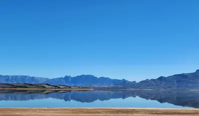 a large body of water with mountains in the background at The 10th Hole - Golf Estate in Villiersdorp