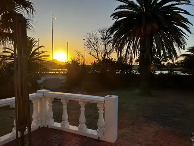 a sunset over a white railing with a palm tree at Lagoon Lodge in Cape Town