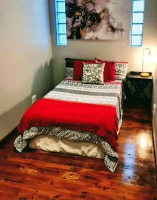 a bedroom with a bed with a red blanket at Mead, Pinelands in Cape Town