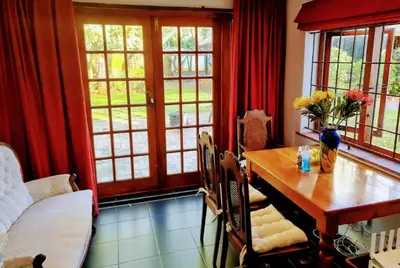 a dining room with a table and chairs and windows at Mead, Pinelands in Cape Town