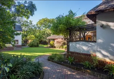 a house with a brick walkway in front of a yard at Mead, Pinelands in Cape Town