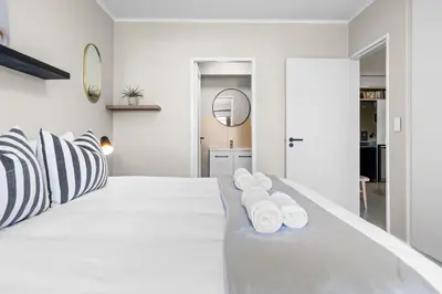 a white bedroom with a large white bed with black and white pillows at Mayfair Luxury 212 by Host Agents in Cape Town