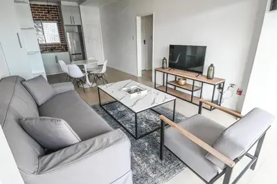 a living room with a couch and a tv and a table at 6 Culemborg Court, 5 Culemborg Street, Strand, Cape Town in Cape Town