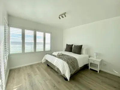 a white bedroom with a bed and a window at Sea Spray Blouberg Beach in Bloubergstrand