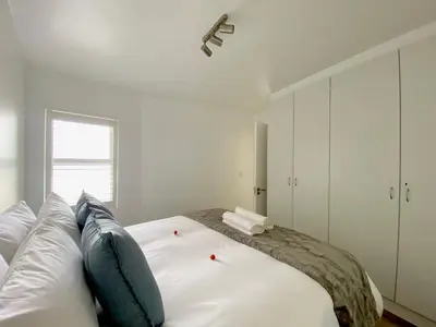 a bedroom with a large white bed with blue pillows at Sea Spray Blouberg Beach in Bloubergstrand