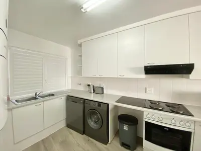 a kitchen with white cabinets and a washing machine at Sea Spray Blouberg Beach in Bloubergstrand
