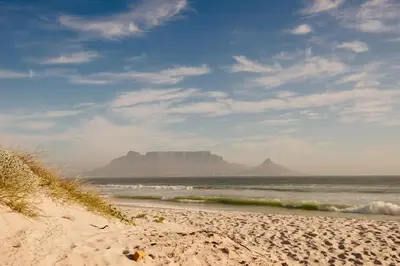 a beach with a view of the ocean and a mountain at Sea Spray Blouberg Beach in Bloubergstrand