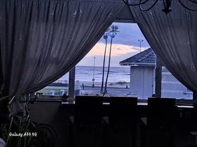 a view of the ocean from a room with curtains at Beach Haven Sea Views, Fritzandi, Strand, Cape Town in Cape Town