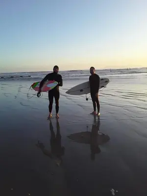 two men standing on the beach with their surfboards at Beach Haven Sea Views, Fritzandi, Strand, Cape Town in Cape Town