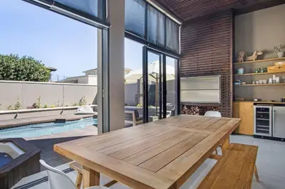 a dining room with a wooden table and a pool at Sunset Links Villa 54 in Cape Town