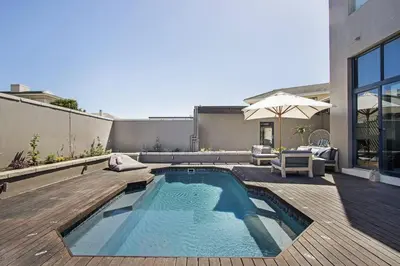 a backyard with a swimming pool and an umbrella at Sunset Links Villa 54 in Cape Town