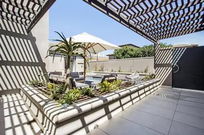 an outdoor patio with chairs and an umbrella at Sunset Links Villa 54 in Cape Town