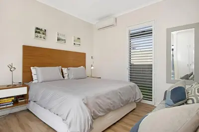 a white bedroom with a large bed and a window at Sunset Links Villa 54 in Cape Town