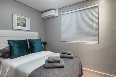 a bedroom with a bed with green pillows on it at Modern Family Flat Andringa Walk in Stellenbosch
