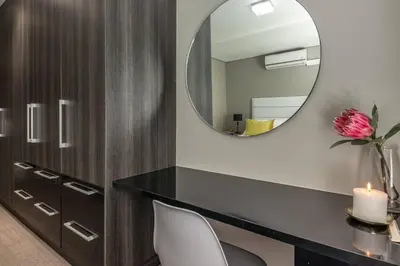 a vanity with a mirror and a desk with a pink flower at Modern Family Flat Andringa Walk in Stellenbosch