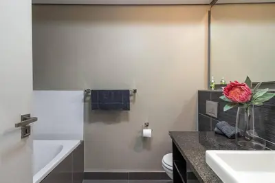 a bathroom with a vase with a flower on a counter at Modern Family Flat Andringa Walk in Stellenbosch